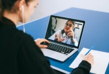 Business professionals participating in a video conference meeting with laptops and screens