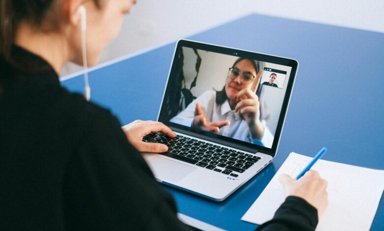 Business professionals participating in a video conference meeting with laptops and screens