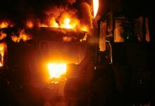 Large industrial fire with flames and smoke against dark sky