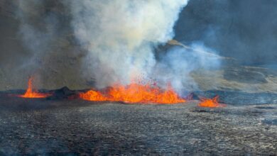 Dramatic volcanic eruption with ash plume rising into dark sky