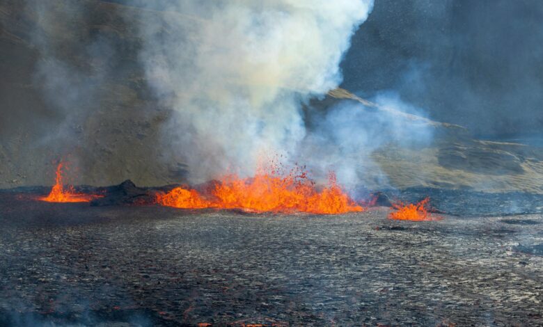 Dramatic volcanic eruption with ash plume rising into dark sky