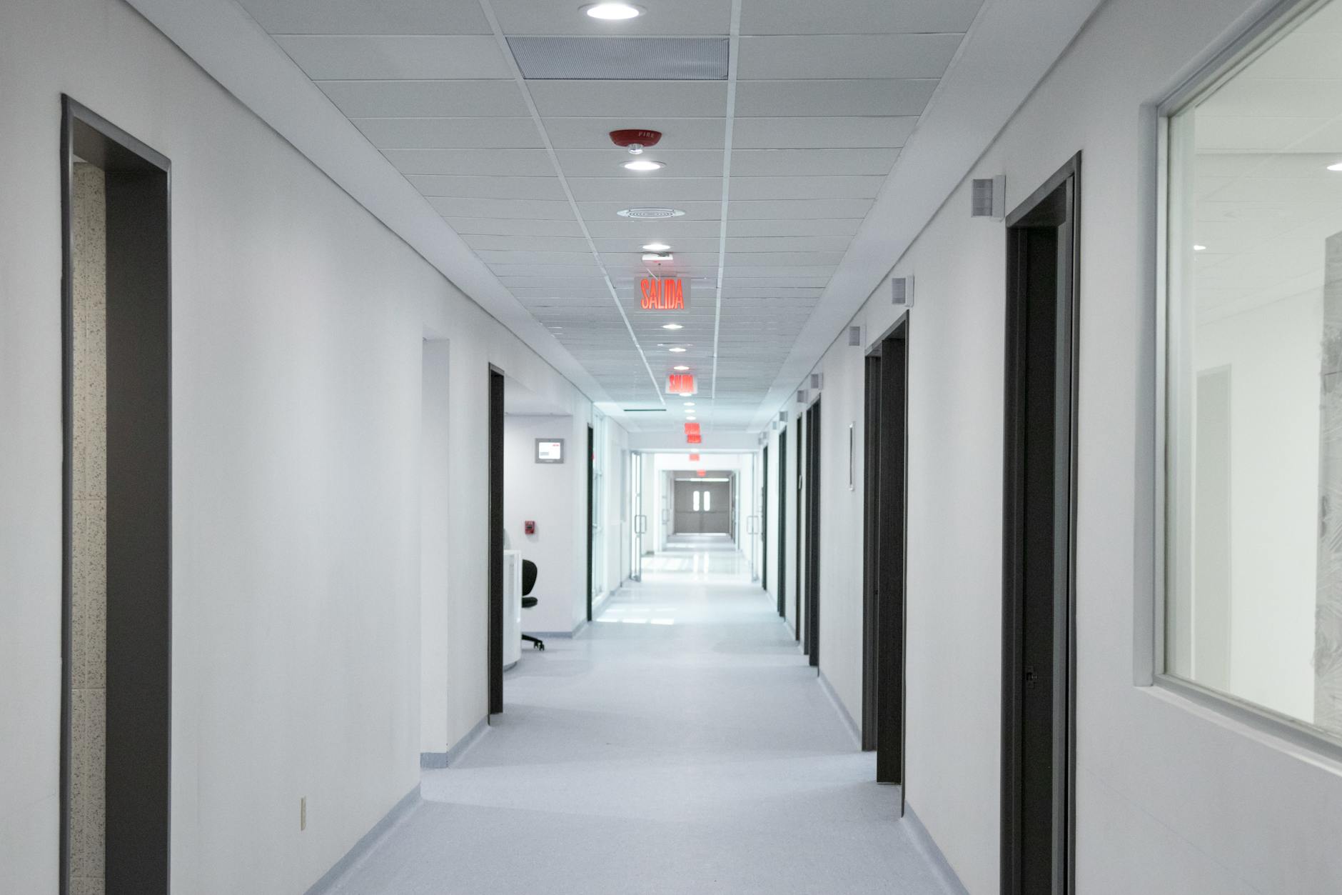 Empty hospital corridor with medical equipment and patient rooms