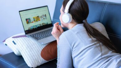 Person watching streaming content on laptop screen in dimly lit room