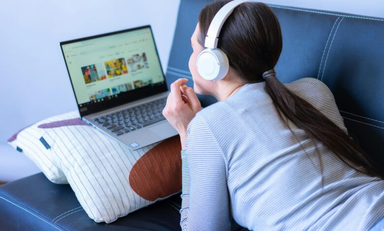 Person watching streaming content on laptop screen in dimly lit room