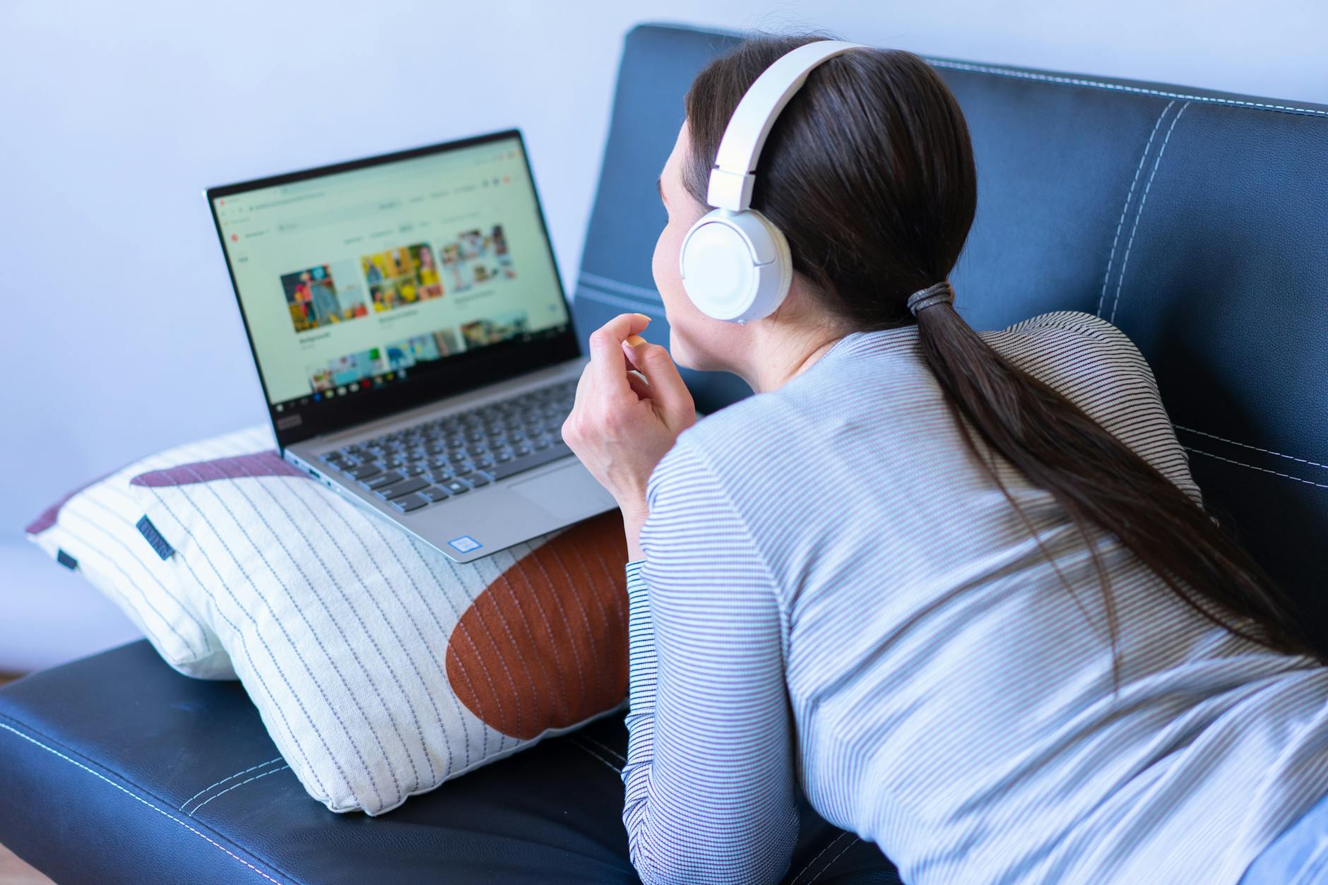 Person watching streaming content on laptop screen in dimly lit room