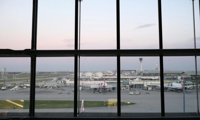 Empty airport terminal with large windows showing heavy snowfall outside during winter storm