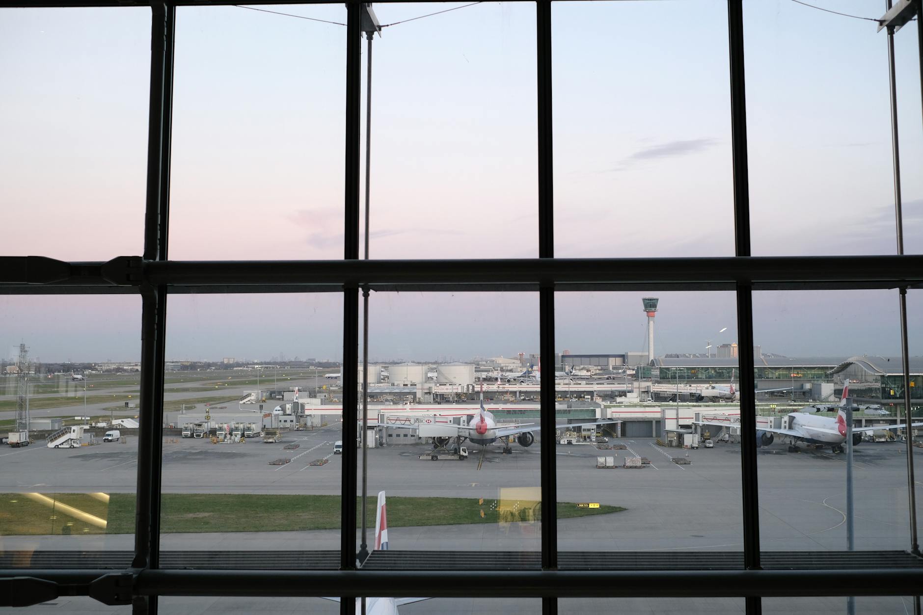 Empty airport terminal with large windows showing heavy snowfall outside during winter storm