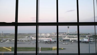 Busy airport terminal with passengers and flight information displays showing delays and cancellations