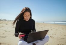 Person working on laptop at tropical beach location representing digital nomad lifestyle
