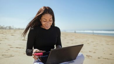 Person working on laptop at tropical beach location representing digital nomad lifestyle