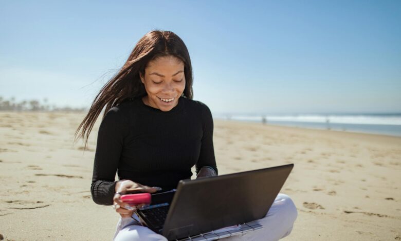 Person working on laptop at tropical beach location representing digital nomad lifestyle
