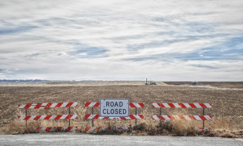 Empty highway with road closure barriers and warning signs blocking traffic