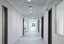 Empty hospital hallway with medical equipment and patient rooms