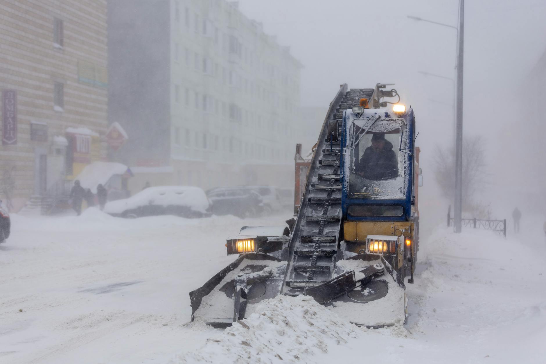 Urban street covered in deep snow with poor visibility during severe winter storm conditions