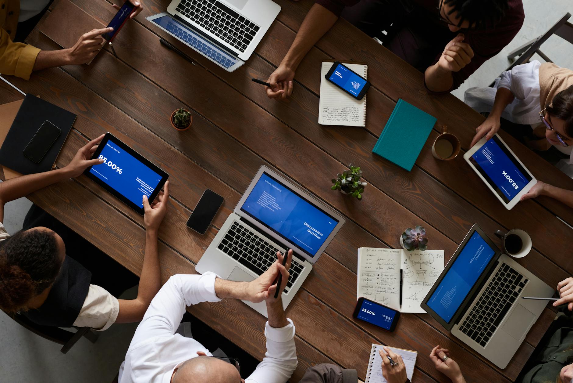 Business professionals in meeting room discussing technology with laptops and digital displays