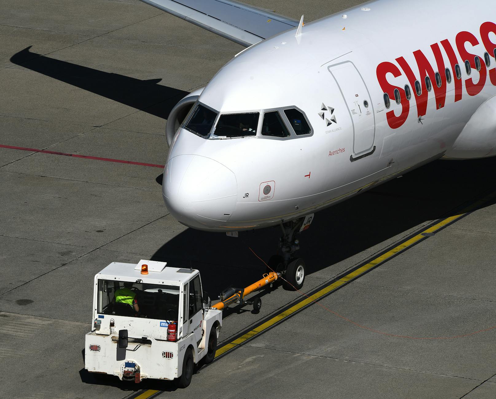 Ground handling workers in safety vests working around aircraft at airport tarmac