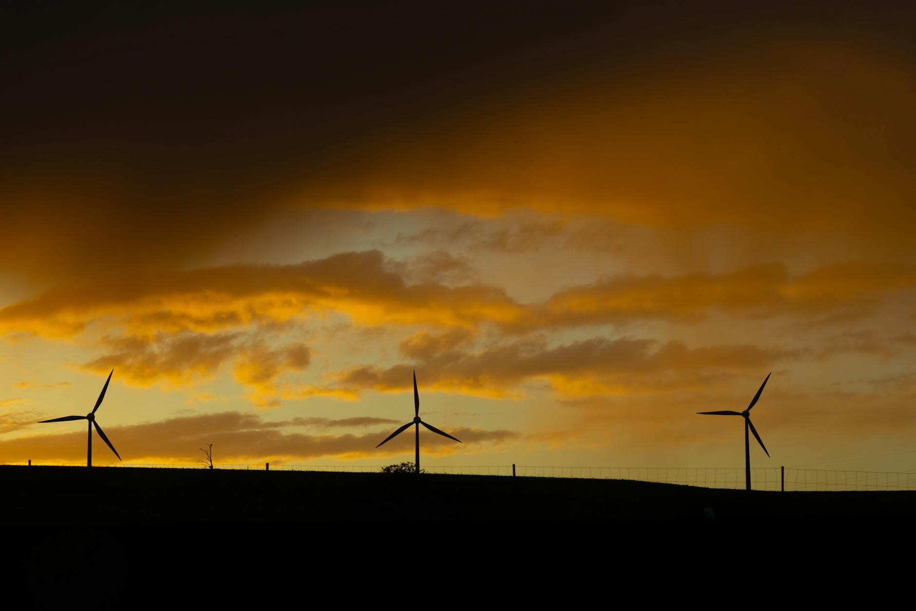 Renewable energy infrastructure silhouetted against dramatic sunset sky