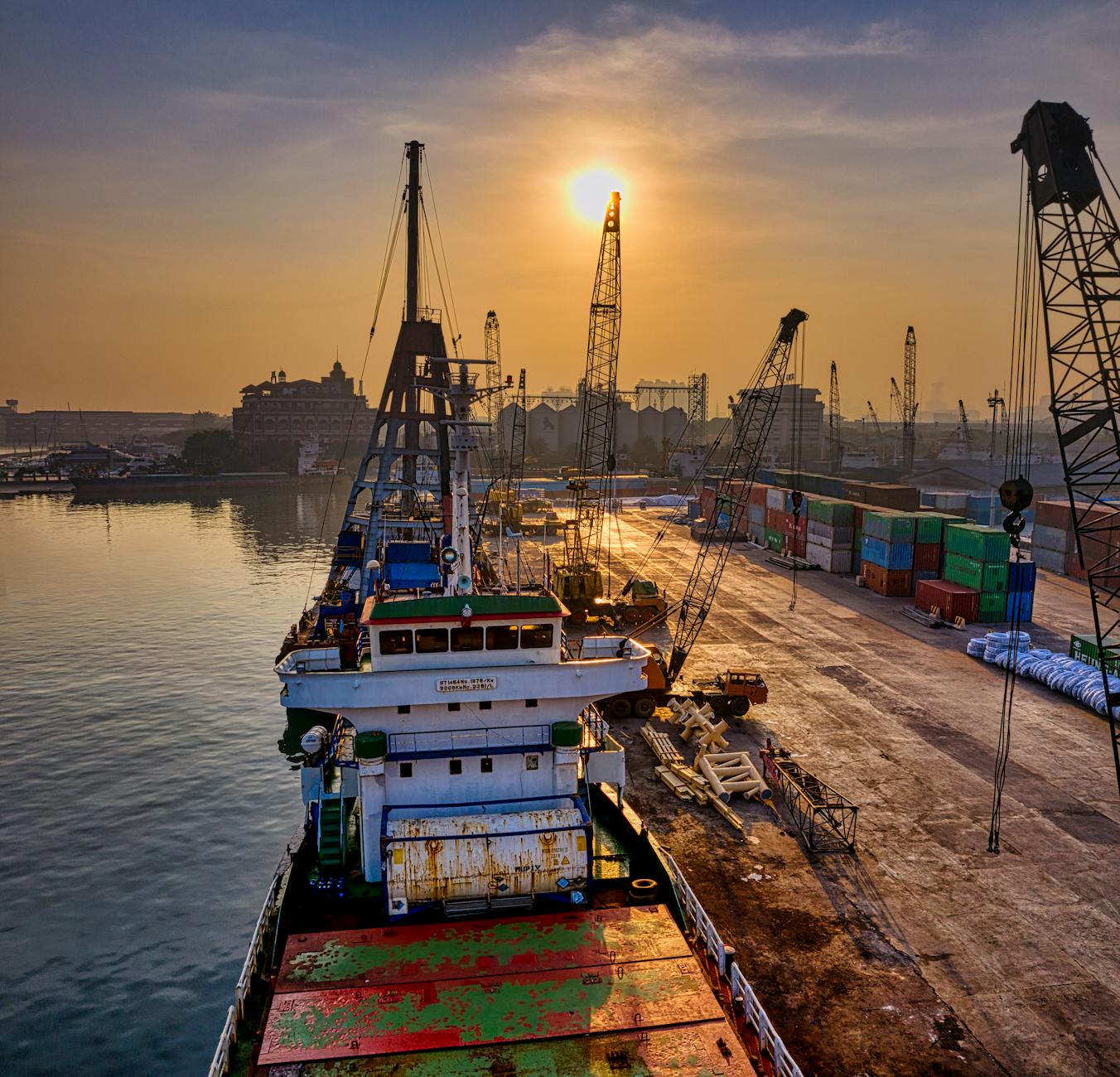Busy cargo port with cranes and shipping containers stacked for loading