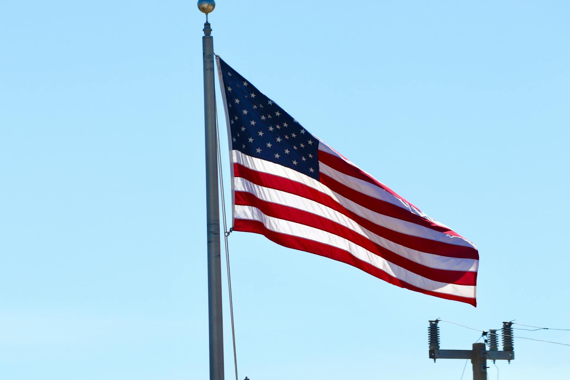 American flag waving on flagpole against blue sky representing national policy