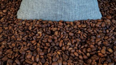 Whole coffee beans spilling from an open bag on a wooden surface