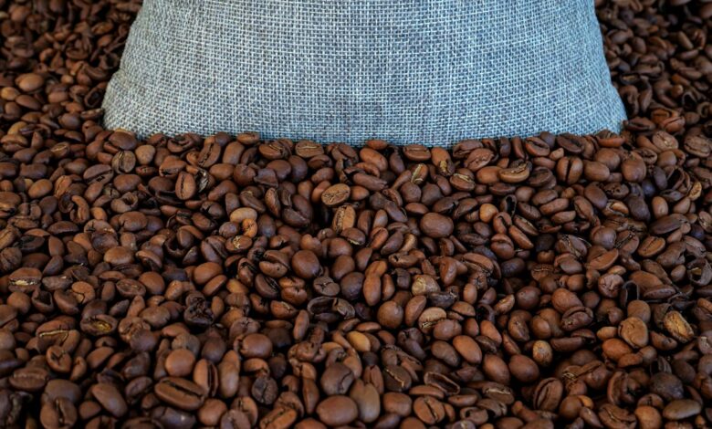 Whole coffee beans spilling from an open bag on a wooden surface