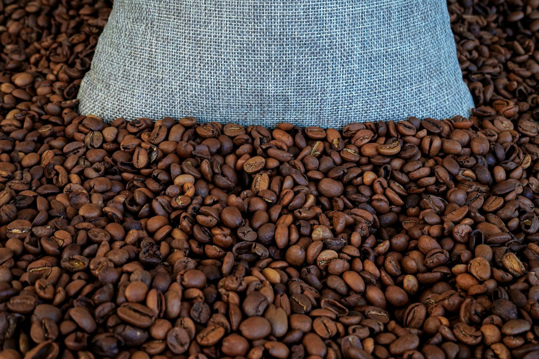 Whole coffee beans spilling from an open bag on a wooden surface