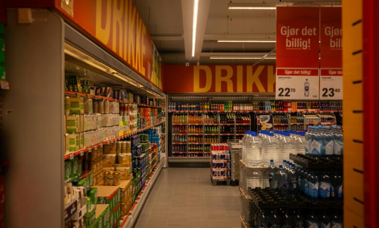 Wide grocery store aisle stocked with packaged food products and fresh produce