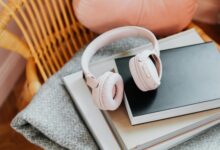 Wireless headphones resting on a stack of books, representing audiobook listening