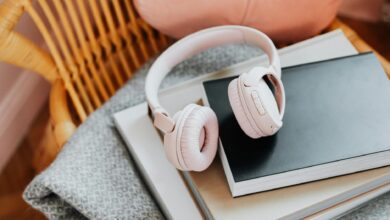 Wireless headphones resting on a stack of books, representing audiobook listening