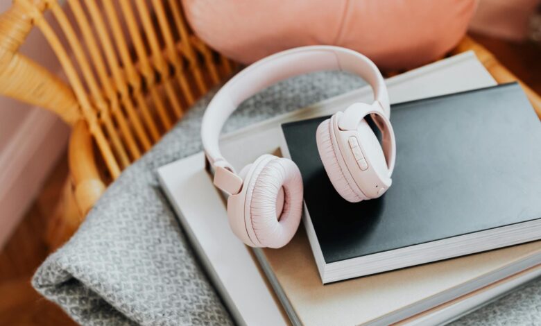 Wireless headphones resting on a stack of books, representing audiobook listening