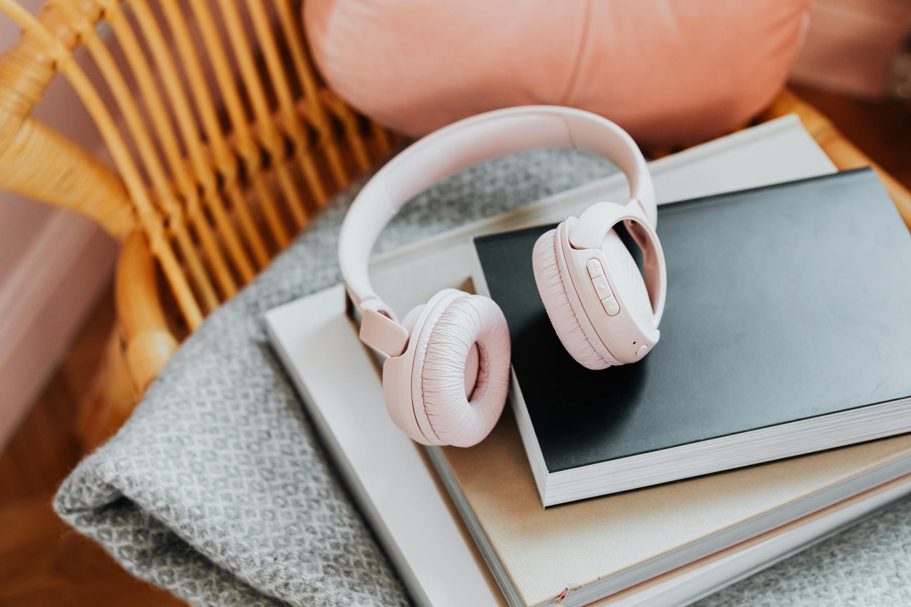 Wireless headphones resting on a stack of books, representing audiobook listening
