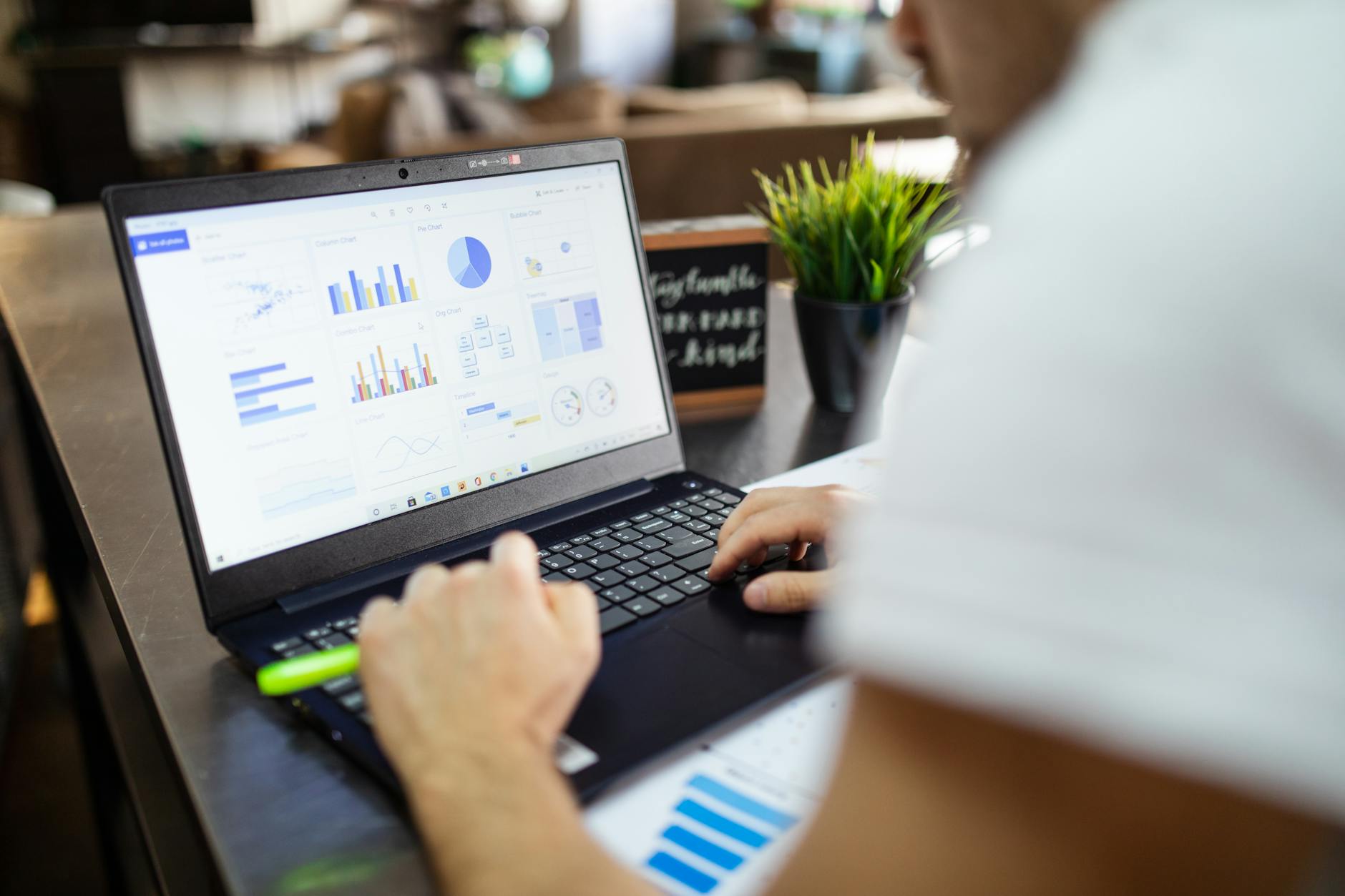 Person analyzing data on a laptop screen in a modern office environment