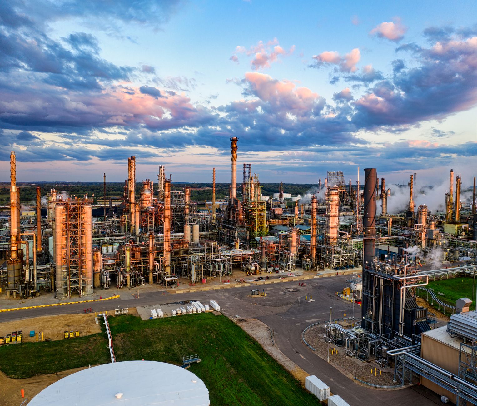 Industrial energy refinery facility at dusk representing fossil fuel infrastructure transition