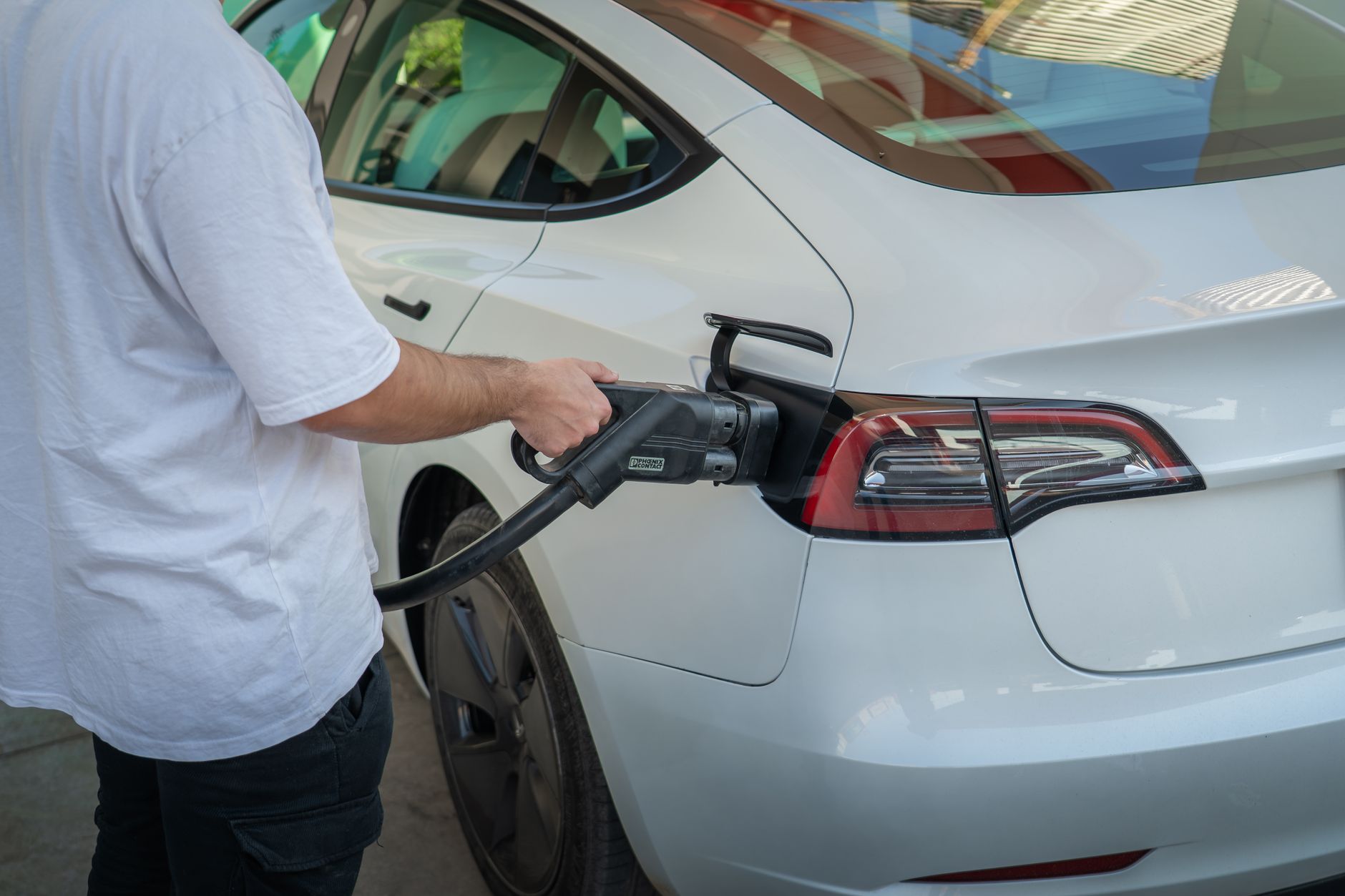 Electric vehicle plugged into a public charging station in an urban setting