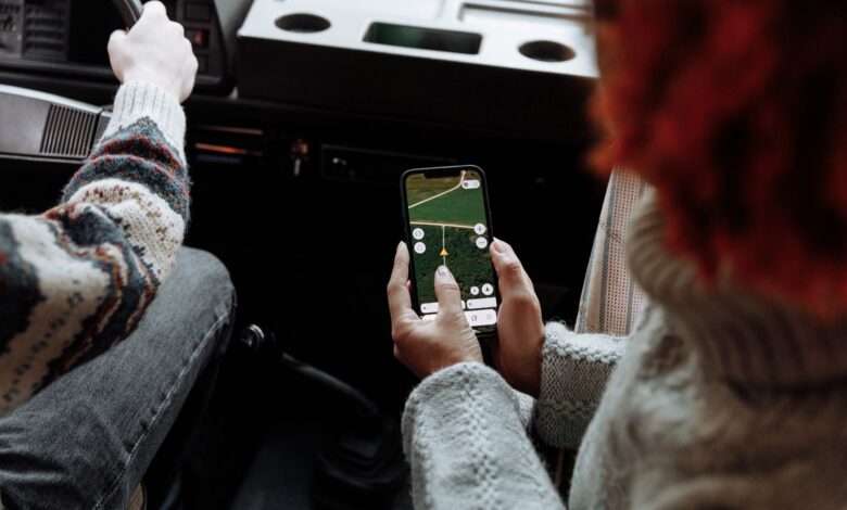 Person using a rideshare app on a smartphone while waiting on a city street
