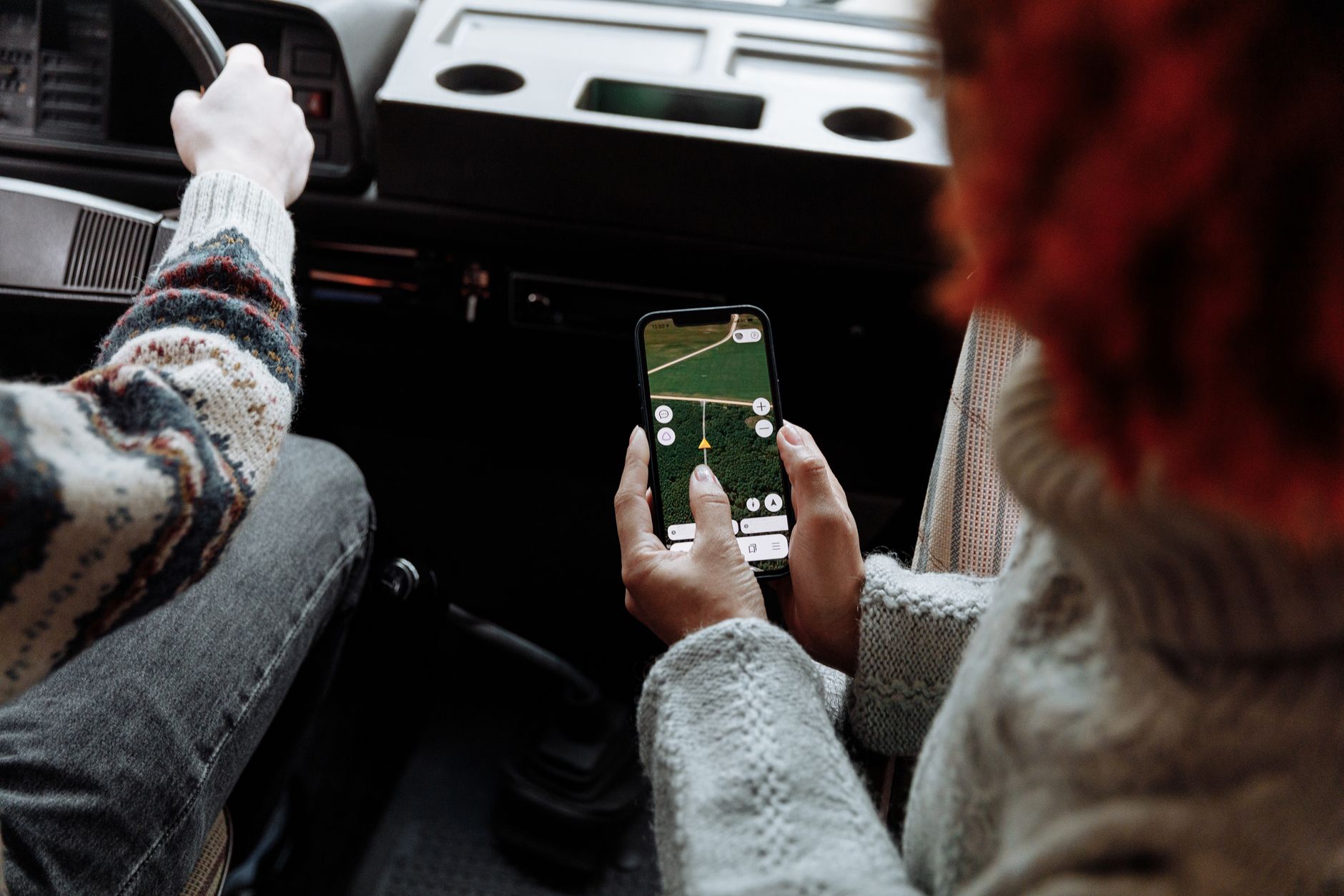 Person using a rideshare app on a smartphone while waiting on a city street