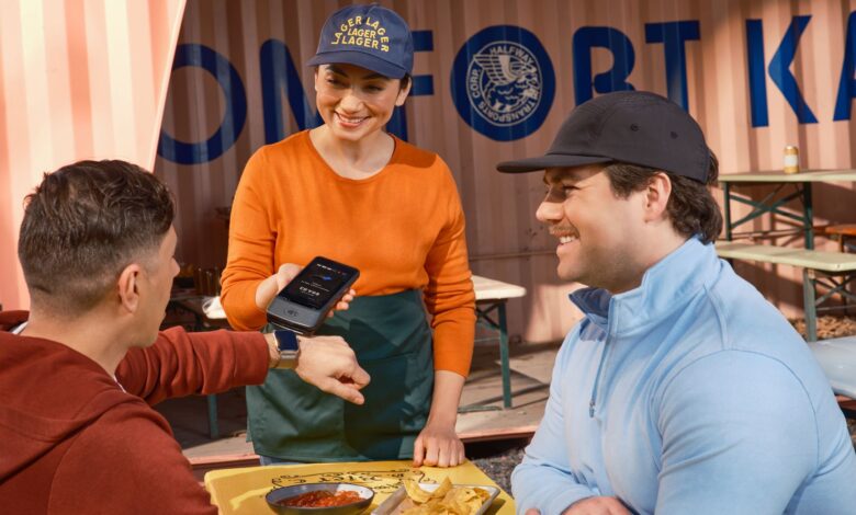 A customer tapping a credit card on a payment terminal at a retail checkout counter