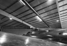 Commercial aircraft on a manufacturing assembly line inside a large factory facility