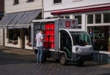 An electric delivery van parked outside a distribution center