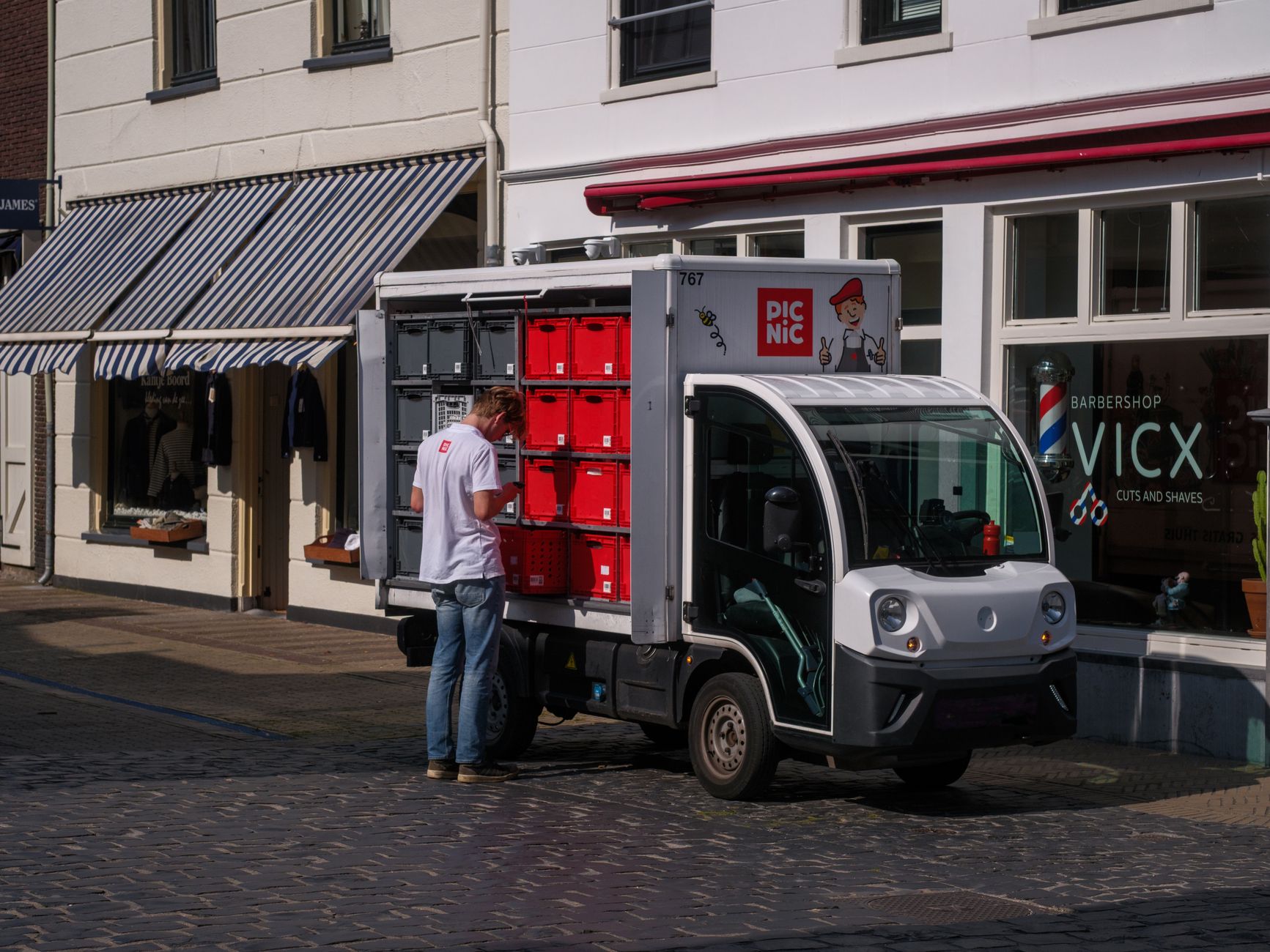 An electric delivery van parked outside a distribution center