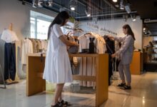 Rows of clothing hanging on retail racks inside a fashion store