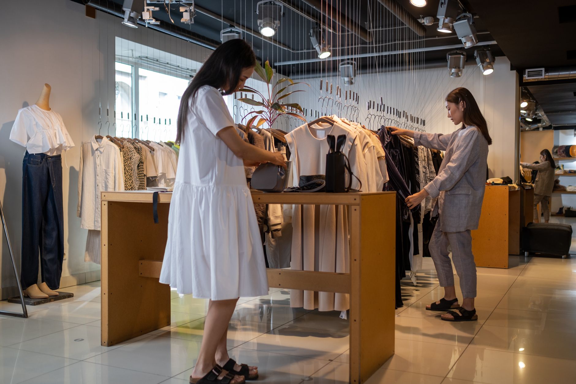 Rows of clothing hanging on retail racks inside a fashion store