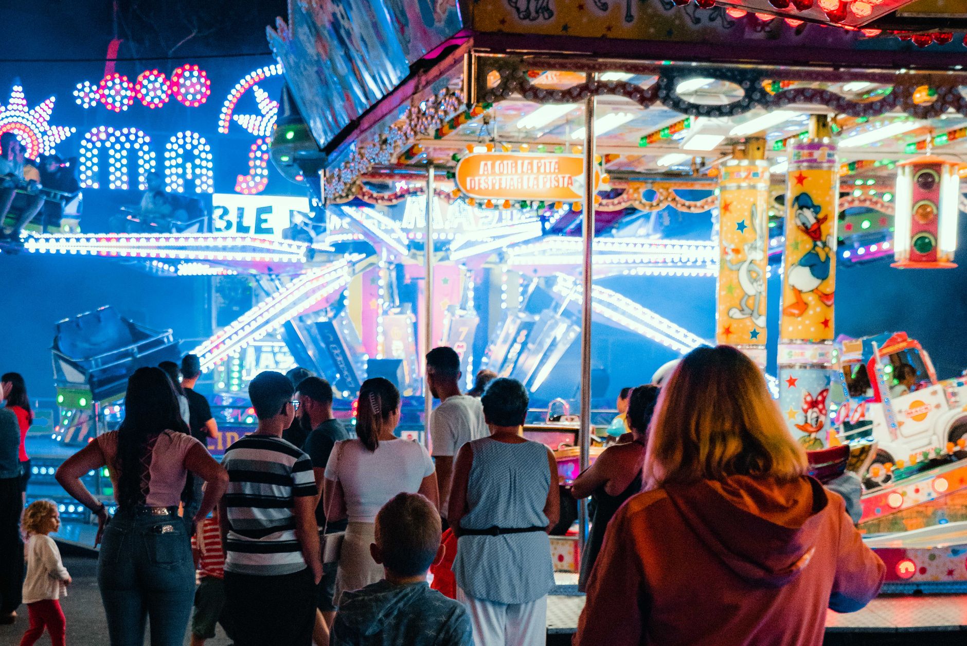Crowds of visitors walking through a large theme park on a busy day