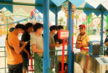 Crowds of visitors walking through a busy theme park on a sunny day