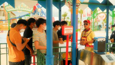 Crowds of visitors walking through a busy theme park on a sunny day
