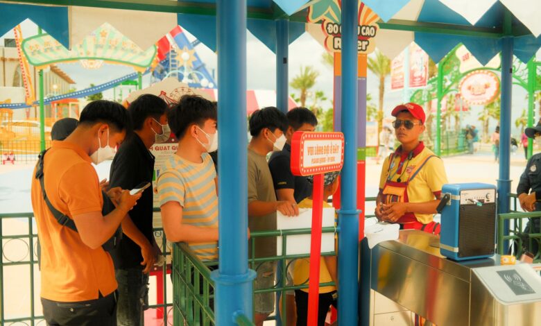Crowds of visitors walking through a busy theme park on a sunny day