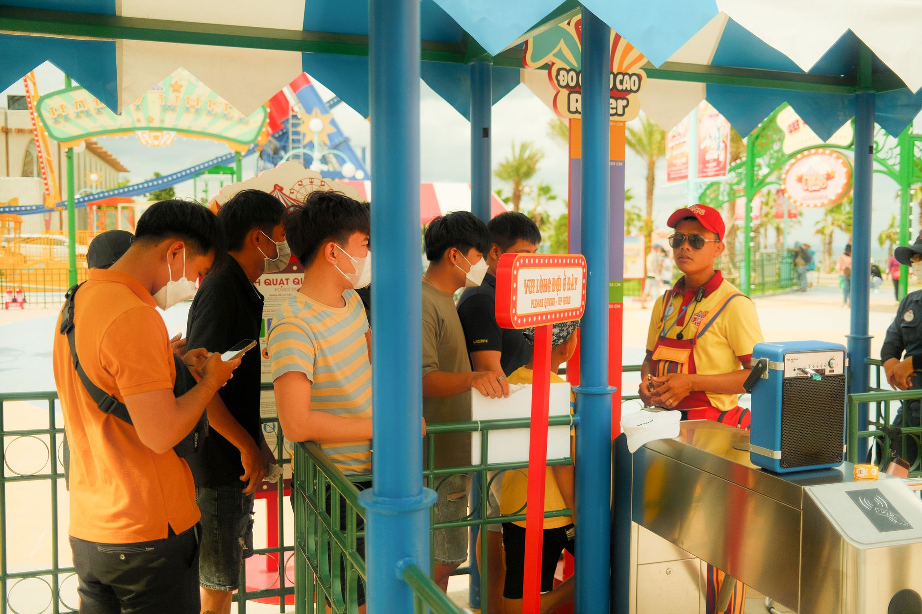 Crowds of visitors walking through a busy theme park on a sunny day