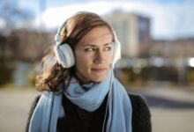 Person wearing headphones listening to audio content on a smartphone