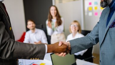 Two business professionals shaking hands over a signed contract representing a corporate operator deal