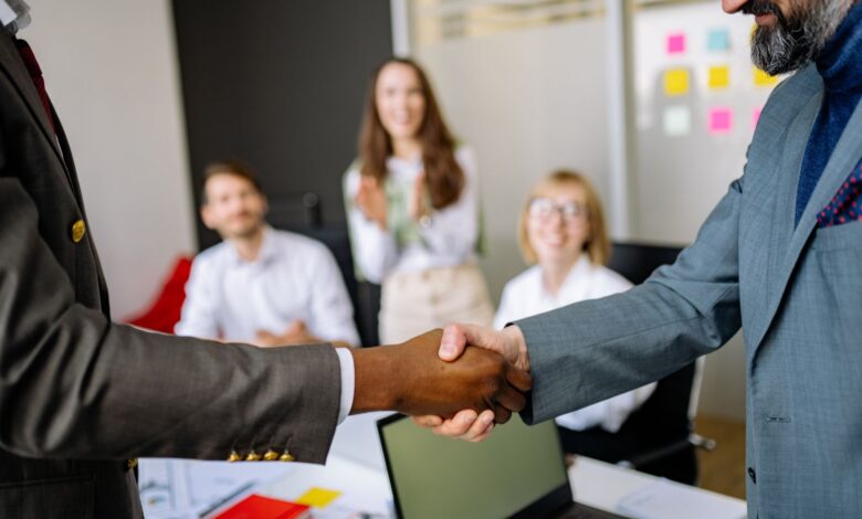 Two business professionals shaking hands over a signed contract representing a corporate operator deal